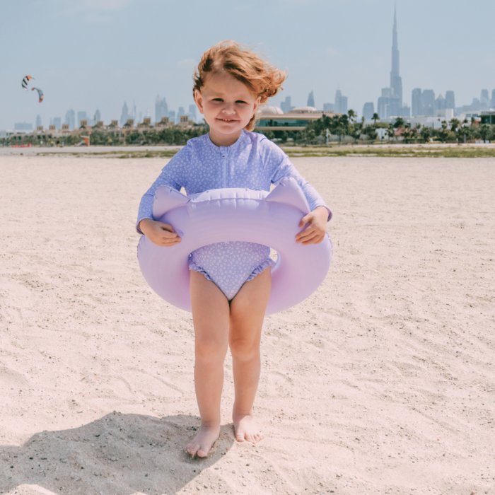 Kid on a beach wearing a swimming purple panther band