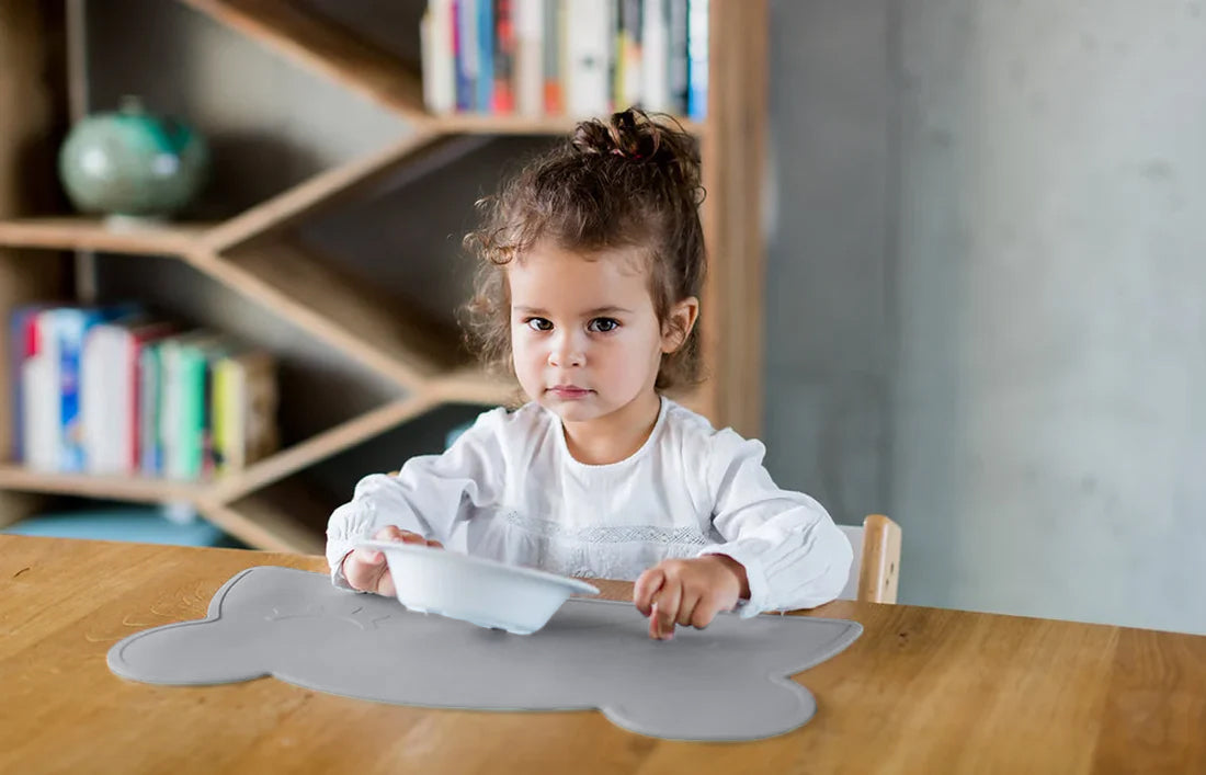 Kid eating on a dark grey bear shaped placemat